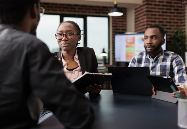 Colleagues team working on company paperwork, doig teamwork to analyze documents and online research information. Planning corporate presentation with data charts, job collaboration.