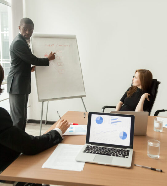 African american businessman giving presentation explains new marketing plan at meeting, black business trainer coach presenting new client management strategy at office training working on flipchart