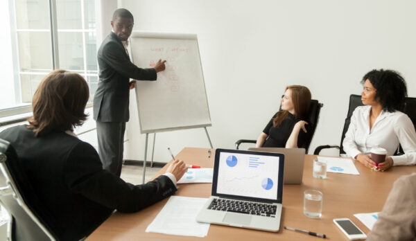 African-american businessman giving presentation explaining new African american businessman giving presentation explains new marketing plan at meeting, black business trainer coach presenting new client management strategy at office training working on flipchart